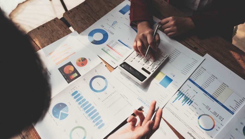 Business People Meeting using laptop computer,calculator,notebook,stock market chart paper for analysis Plans to improve quality next month. Conference Discussion Corporate Concept....