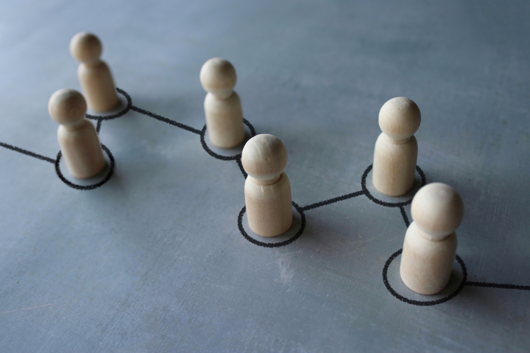 Selective focus image chain of wooden dolls connected by lines. Cooperation, interaction, communication and disseminating information concept