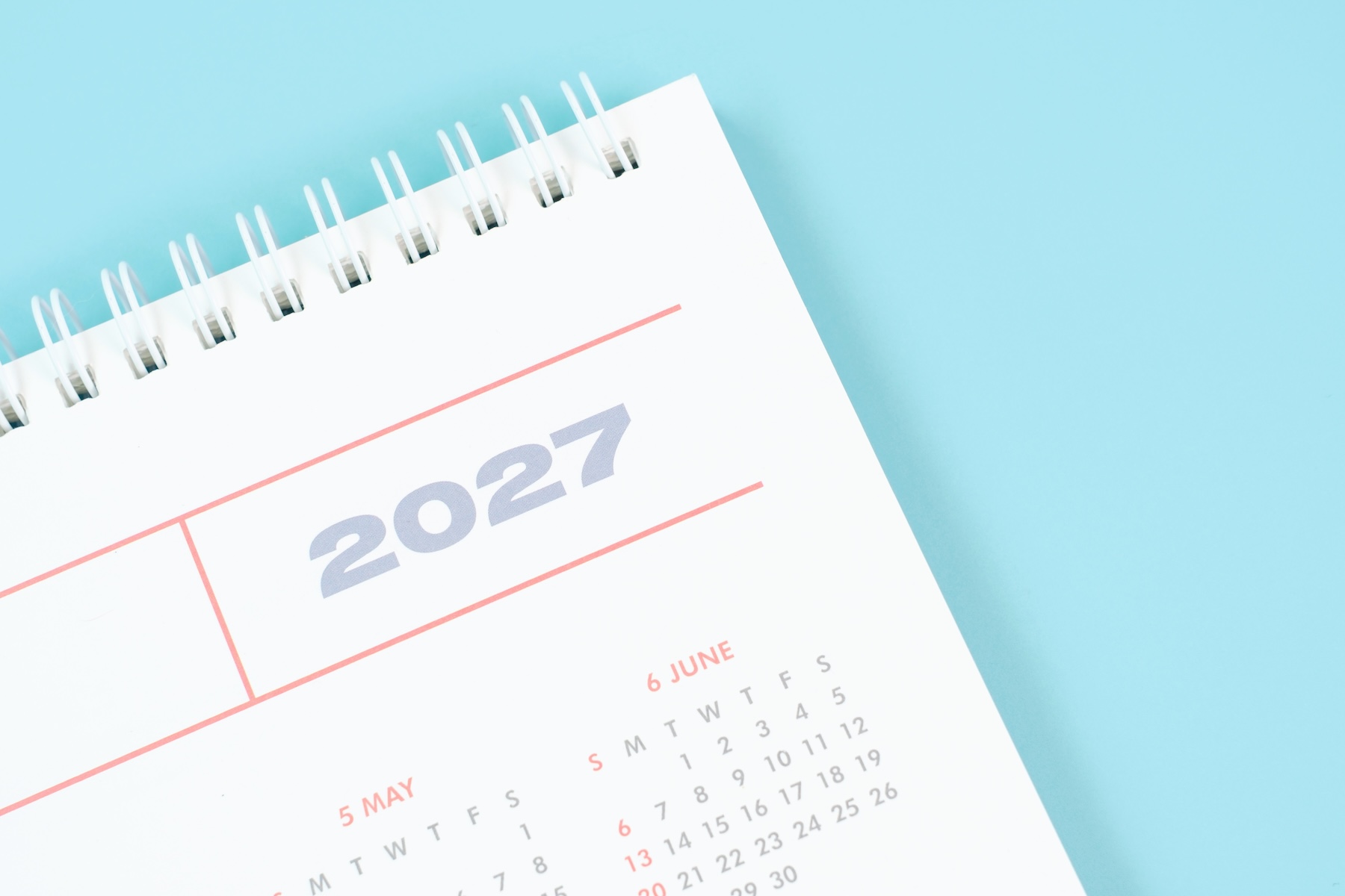 Paper calendar for 2027 on blue background close up top view.